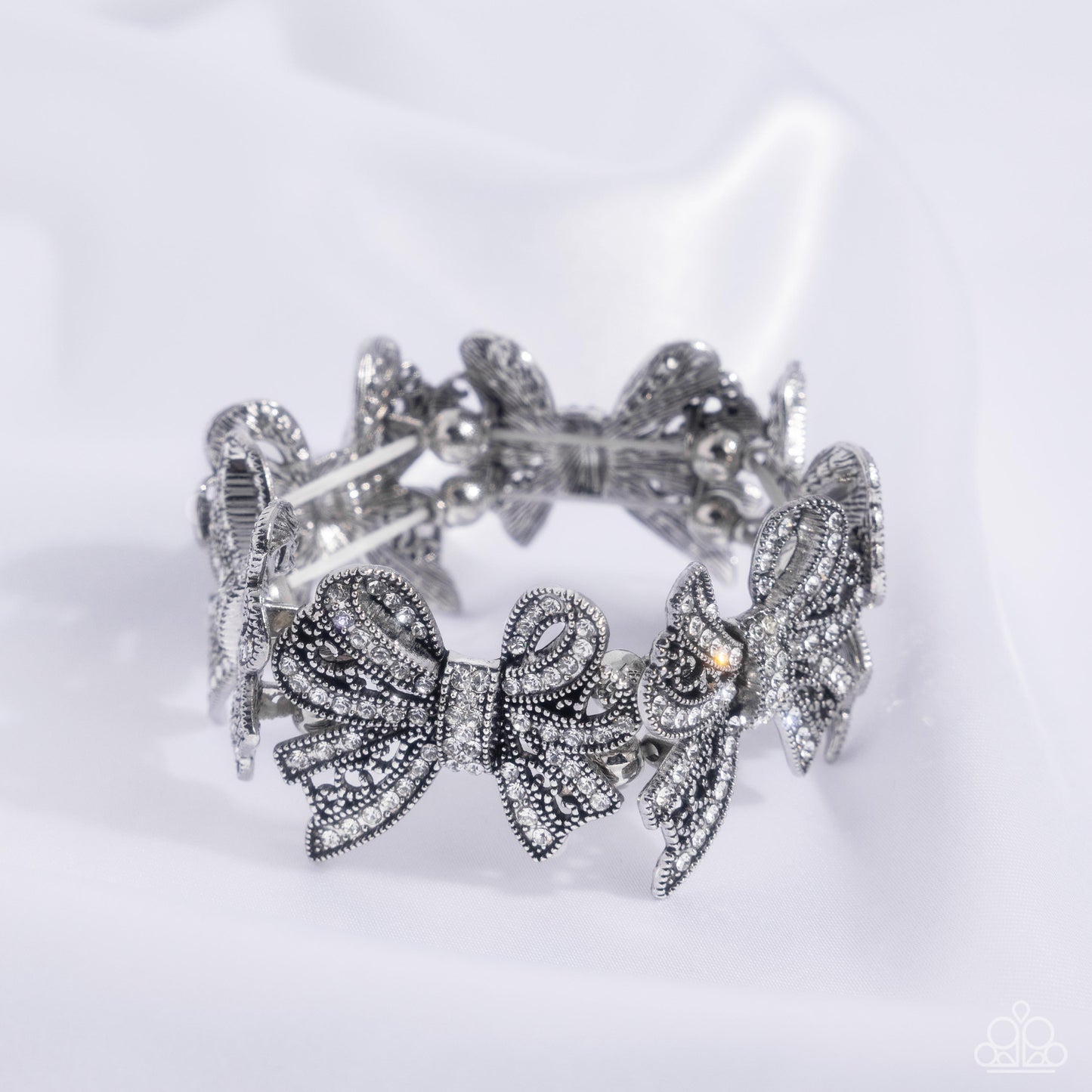 French Flourish - White Rhinestone Bow Stretch Bracelet Life Of The Party October 2024 Paparazzi B1880